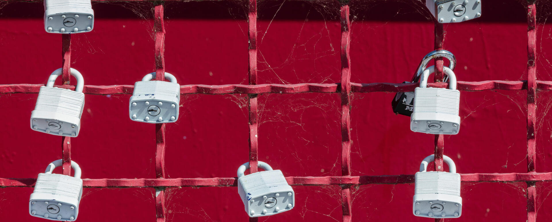 Grey padlocks at red fence - symbol of security