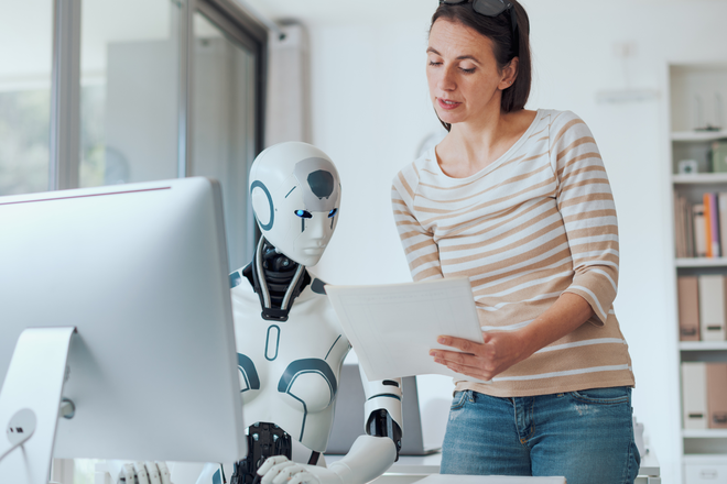 Redaktor treści przegląda wydrukowane strony z humanoidalnym robotem przy biurku - metafora współpracy człowieka i AI przy treści answer-first.