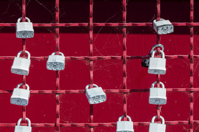 Grey padlocks at red fence - symbol of security