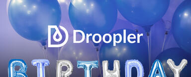 Logo Droopler. Poniżej ręce trzymające baloniki układające się w słowo "birthday". Niebieskie balony w tle. 
