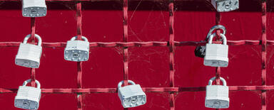 Grey padlocks at red fence - symbol of security
